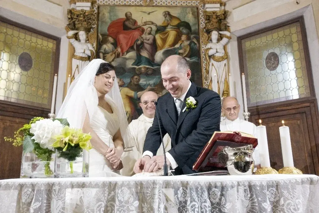 Caterina e Matteo all'altare durante la cerimonia, davanti alla pala e ai celebranti