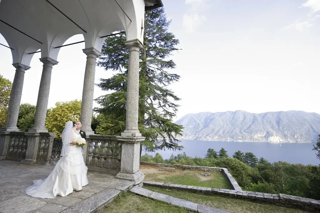 Gli sposi si baciano sotto il porticato del Sacro Monte di Ghiffa, con il Lago Maggiore sullo sfondo