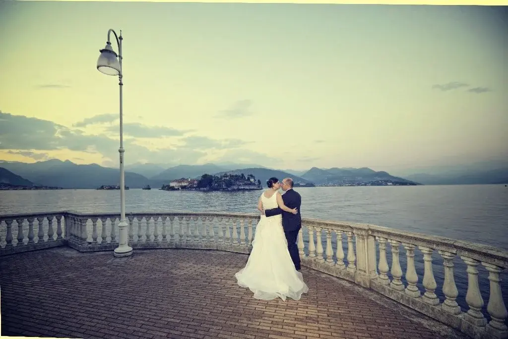 Gli sposi abbracciati al crepuscolo su una terrazza con balaustra sul Lago Maggiore, davanti alle isole